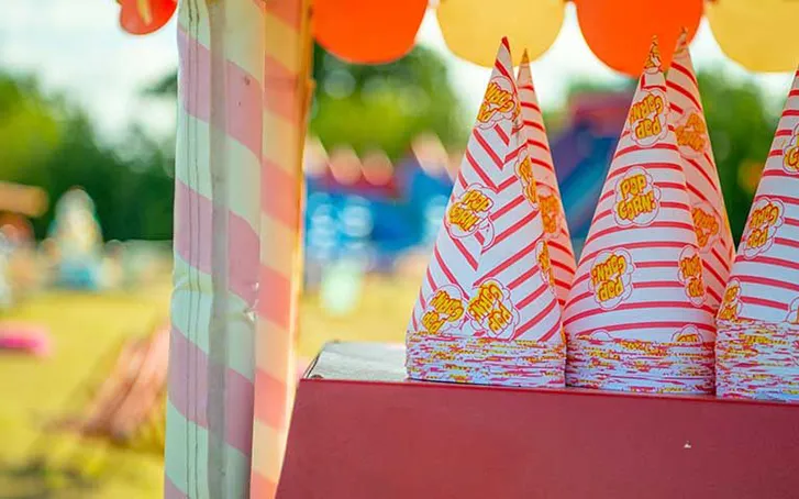 Popcorn cones on a popcorn machine in a field at a company event
