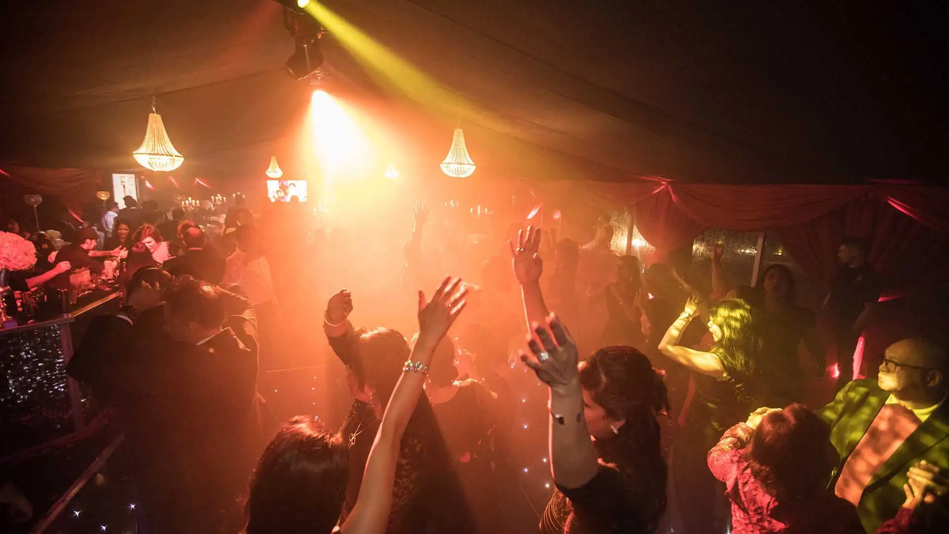 People dancing at party in marquee, dark lighting