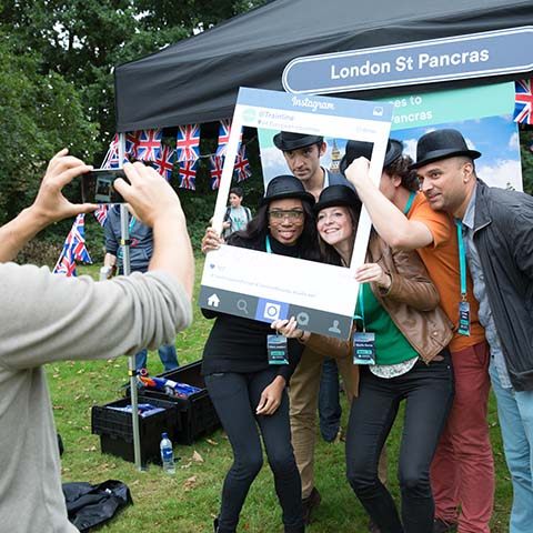 A group of people holding up an Instagram selfie window whilst a colleague takes a photo of them